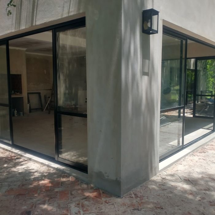 Cerramiento de esquina con grandes paños vidriados y aluminio negro