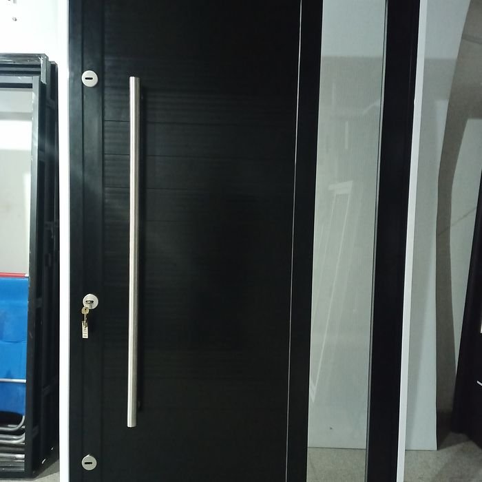 Puerta de entrada pivotante en aluminio negro con paño fijo lateral