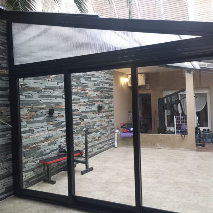 Cerramiento de aluminio con puerta corrediza y techo de policarbonato